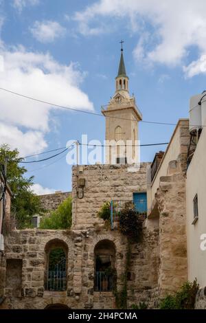 Jerusalem, Israel - 23. September 2021: Ein Kirchturm, der über alten Häusern im malerischen Viertel ein Karem in Jerusalem, Israel, thront Stockfoto