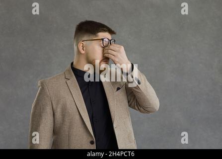 Müde Mann reiben seine angespannten Augen nach einem langen Arbeitstag voller Stress und Probleme Stockfoto