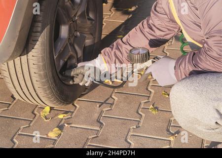 Autoservice. Männliche Hand in Handschuhen prüft den Druck in Autoreifen an sonnigen Tagen. Konzept für die automatische Wartung. Stockfoto