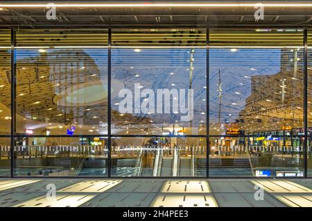 Delft, Niederlande, 29. Oktober 2021: Blick durch die Glasfassade des Hauptbahnhofs zur Bahnhofshalle mit Rolltreppen und Skulpturen Stockfoto