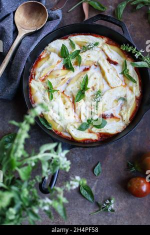 Overhead von Conchigliei, gefüllte Pasta-Schalen, mit Ricotta-Käse, Mozerella und Basilikum Blätter in einer gusseisernen Pfanne. Unscharfer Hintergrund und Vordergrund. Stockfoto