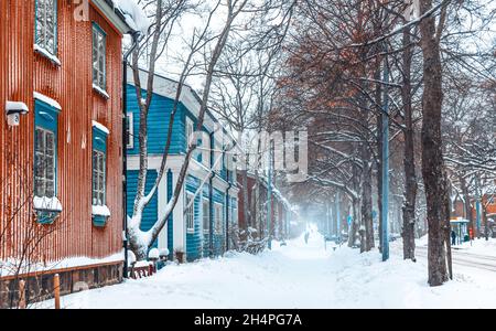 Finnischer Winter. Schneebedeckter Fußweg mit Schneeverwehungen in der Stadt. Eine Straße mit bunten Gebäudefassaden. Traditionelle alte Holzhäuser. Helsinki Finnland. Stockfoto