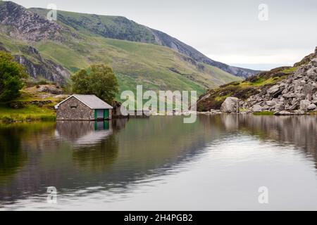 Das Bootshaus von Llyn Ogwen spiegelt sich an einem grauen, regnerischen Sommertag in Llyn Ogwen wider Stockfoto