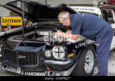 Mechaniker bereitet den 1970 Chevrolet Camaro Z28 Gerry Marshall Trophy Teilnehmer in der Fahrerlager-Garage auf dem Goodwood 78. Mitgliedertreffen, Sussex, Großbritannien, vor. Stockfoto