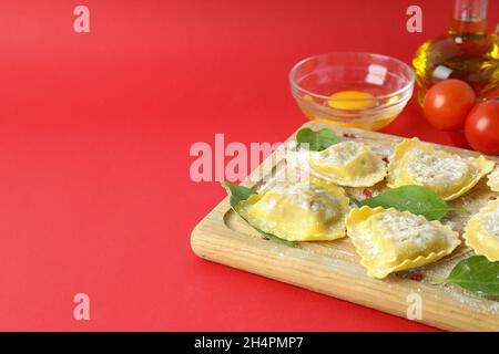 Konzept des Kochens von Ravioli auf rotem Hintergrund Stockfoto