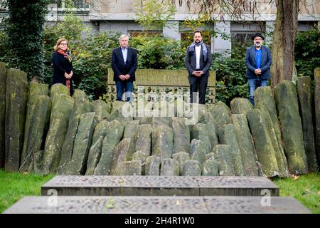 04. November 2021, Niedersachsen, Oldenburg: Christiane Cordes (l-r), Leiterin des Büros für Kultur, Museen und Sport, Dietmar Schütz, Vorsitzender der Bürgerstiftung Oldenburg, Maximilian Strnad, Mitarbeiterin in der Koordinierungsstelle für Gedenkzeichen der Stadt München, Und Farschid Ali Zahedi, Gründer des Vereins Werkstattfilm, stehen neben einem Denkmal für die Opfer des Nationalsozialismus in der Innenstadt. Mit neuen Wandtafeln und Stelen will die Stadt Oldenburg den Opfern der Nazi-Verbrechen gedenken. In den kommenden Wochen werden die Gedenkschilder angebracht Stockfoto