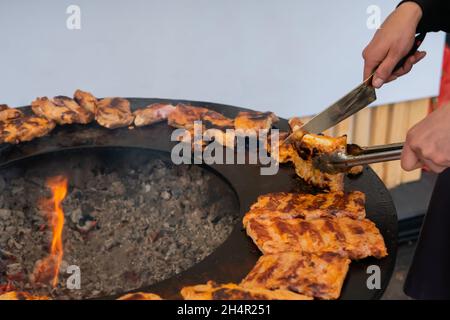 Koch hält Messer und schneidet frische, saftige Fleischsteaks auf dem Brazier Stockfoto