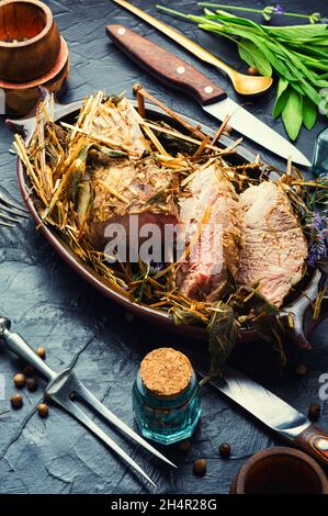 Appetitliches Fleisch in frischem Heu geschmort.gebratener Schweinelende in hays. Stockfoto