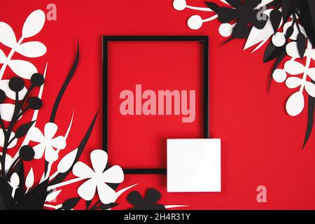 Schwarzer Rahmen auf rot-weißen, papiergeschnittenen Blättern Stockfoto
