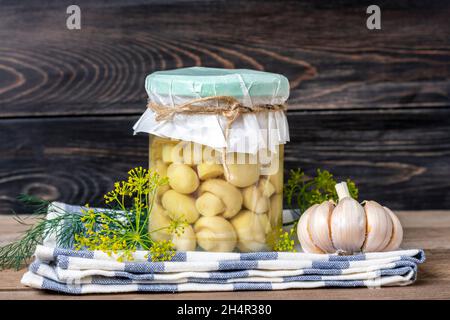 Hausgemachte eingelegte Champignons, Knoblauch in Gläsern auf Holzregal hausgemachte Konserven und fermentierte Lebensmittel Konzept saisonale Produkt. Stockfoto