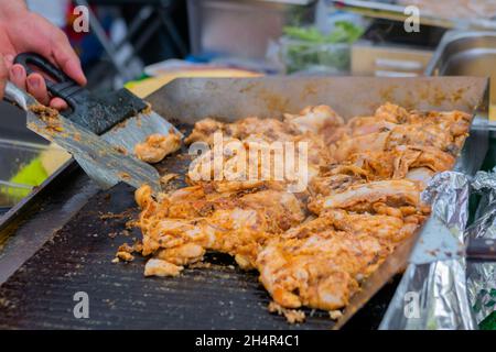 Koch bereitet Hühnerfleisch auf dem Grill beim Street Food Festival zu Stockfoto