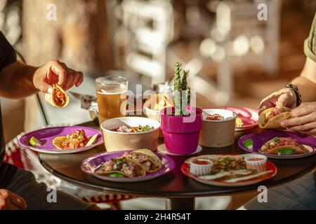 Serviert wird ein traditioneller mexikanischer Tisch. Outdoor Food Konzept . Eine nicht erkennbare Gruppe von Freunden, die in einem Restaurant mexikanisches Essen aßen. Stockfoto