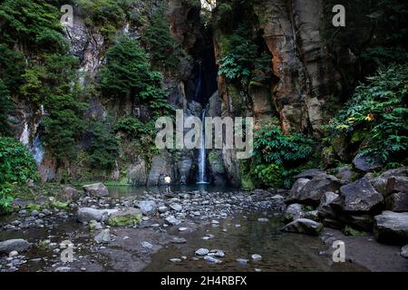 Junge, der in der Nähe eines Cascata do Salto do Cabrito Wasserfalls auf der Insel Sao Miguel, Azoren, Portugal, steht Stockfoto