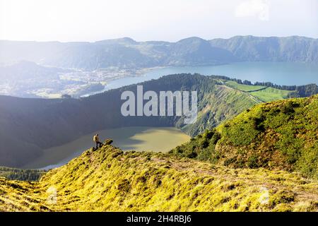 Touristenwanderung zum Aussichtspunkt Miradouro da Boca do Inferno mit Lagoa Verde, Lagoa Azul und dem Ozean im Hintergrund. Sete Cidades, Azoren Stockfoto