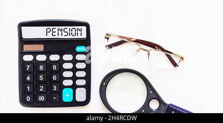 Taschenrechner mit dem Wort Pension auf dem Display, neben einer Brille und einer Lupe auf weißem Hintergrund. Stockfoto