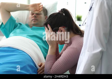 Mädchen weint in der Nähe eines Mannes, der in der Klinik auf dem Bett liegt Stockfoto