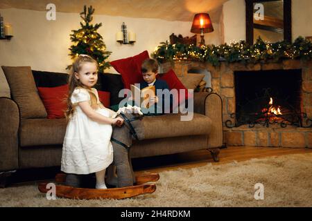 Bruder und Schwester verbringen in Erwartung des neuen Jahres Zeit in dem mit Girlanden geschmückten Zimmer. Selektiver Weichfokus, Filmkorneffekt Stockfoto