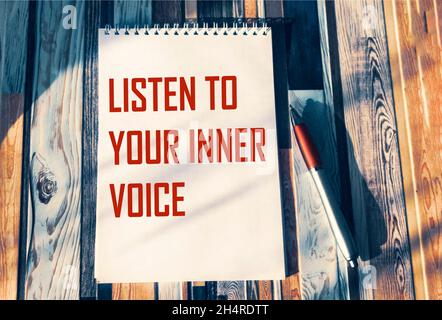 Hören Sie auf Ihre innere Stimme - inspirierende Phrase auf einem Notizbuch. Vertrauen, Intuition und das Konzept der persönlichen Entwicklung Stockfoto