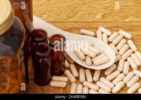 Löffel mit den Pillen mit dem pflanzlichen medizinischen Pulver auf dem Holztisch. Konzepte und Hintergründe für Gesundheit und Homöopathie Stockfoto