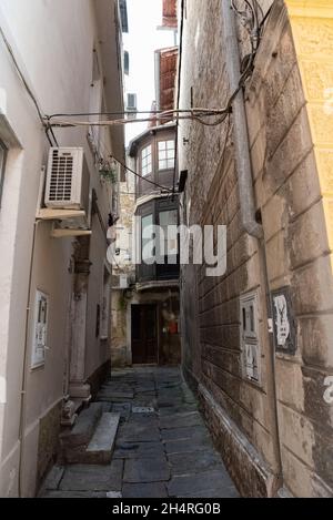 Koper, Slowenien - 12. Juli 2021: Enge Gassen zwischen Mietshäusern in der Altstadt. Alte Gebäude in einer Hafenstadt an der Adria. Stockfoto