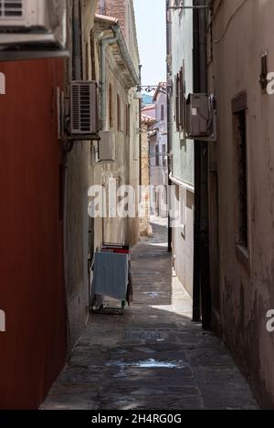 Koper, Slowenien - 12. Juli 2021: Enge Gassen zwischen Mietshäusern in der Altstadt. Alte Gebäude in einer Hafenstadt an der Adria. Stockfoto