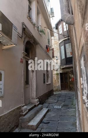 Koper, Slowenien - 12. Juli 2021: Enge Gassen zwischen Mietshäusern in der Altstadt. Alte Gebäude in einer Hafenstadt an der Adria. Stockfoto