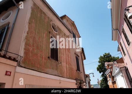 Koper, Slowenien - 12. Juli 2021: Enge Gassen zwischen Mietshäusern in der Altstadt. Alte Gebäude in einer Hafenstadt an der Adria. Stockfoto