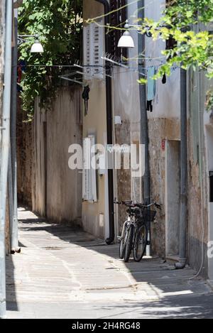 Koper, Slowenien - 12. Juli 2021: Enge Gassen zwischen Mietshäusern in der Altstadt. Alte Gebäude in einer Hafenstadt an der Adria. Stockfoto