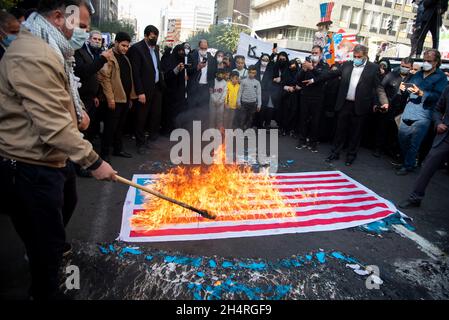 Teheran, Iran. November 2021. Demonstranten zünden bei einer Kundgebung vor der ehemaligen US-Botschaft zum Gedenken an den Jahrestag ihrer Beschlagnahme im Jahr 1979 in Teheran, Iran, am Donnerstag, den 4. November 2021, eine verspottete US-Flagge an. Die Übernahme der Botschaft löste eine 444-tägige Geiselkrise und einen Bruch der diplomatischen Beziehungen aus, die bis heute andauert. (Foto: Sobhan Farajvan/Pacific Press/Sipa USA) Quelle: SIPA USA/Alamy Live News Stockfoto