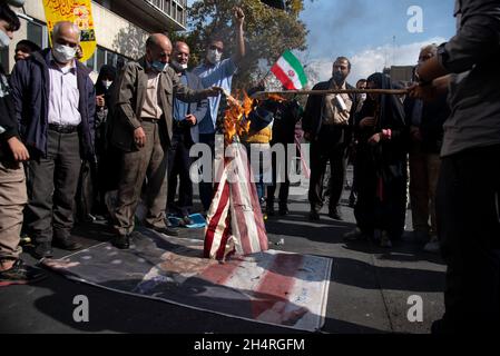 Teheran, Iran. November 2021. Demonstranten zünden bei einer Kundgebung vor der ehemaligen US-Botschaft zum Gedenken an den Jahrestag ihrer Beschlagnahme im Jahr 1979 in Teheran, Iran, am Donnerstag, den 4. November 2021, eine verspottete US-Flagge an. Die Übernahme der Botschaft löste eine 444-tägige Geiselkrise und einen Bruch der diplomatischen Beziehungen aus, die bis heute andauert. (Foto: Sobhan Farajvan/Pacific Press/Sipa USA) Quelle: SIPA USA/Alamy Live News Stockfoto