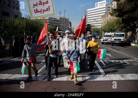 Teheran, Iran. November 2021. Demonstranten halten bei einer Kundgebung vor der ehemaligen US-Botschaft zum Gedenken an den Jahrestag ihrer Beschlagnahme im Jahr 1979 in Teheran, Iran, am Donnerstag, den 4. November 2021, ein US-amerikanisches Plakat und eine iranische Flagge. Die Übernahme der Botschaft löste eine 444-tägige Geiselkrise und einen Bruch der diplomatischen Beziehungen aus, die bis heute andauern (Foto: Sobhan Farajvan/Pacific Press/Sipa USA) Quelle: SIPA USA/Alamy Live News Stockfoto