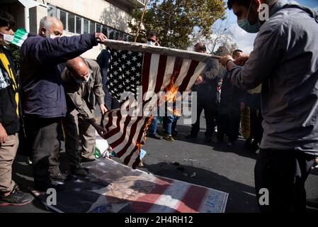 Teheran, Iran. November 2021. Demonstranten zünden bei einer Kundgebung vor der ehemaligen US-Botschaft zum Gedenken an den Jahrestag ihrer Beschlagnahme im Jahr 1979 in Teheran, Iran, am Donnerstag, den 4. November 2021, eine verspottete US-Flagge an. Die Übernahme der Botschaft löste eine 444-tägige Geiselkrise und einen Bruch der diplomatischen Beziehungen aus, die bis heute andauert. (Foto: Sobhan Farajvan/Pacific Press/Sipa USA) Quelle: SIPA USA/Alamy Live News Stockfoto