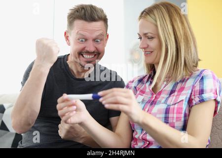 Portrait von glücklichen Mann bekam Nachrichten über Ehefrauen Schwangerschaft, Warten auf Baby, fröhliche Mann zeigen ja Geste. Frau mit positivem Schwangerschaftstest. Familie Stockfoto