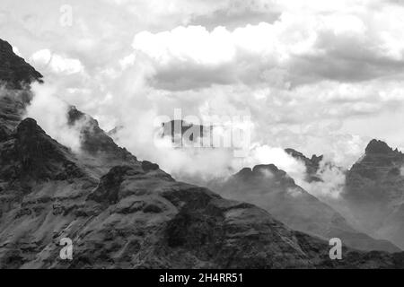 Wolken sammeln sich zwischen den hohen zerklüfteten Basaltspitzen der Drakensberger Berge, Teil des großen Escarpment von Südafrika, in Schwarz und Weiß. Stockfoto