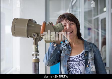 Das Mädchen blickt durch ein Binoskop auf das Panorama von Nowosibirsk. Das Konzept des Tourismus, Reisen. Gemischte Medien Stockfoto