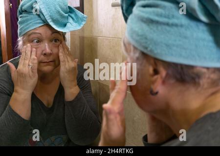 Ältere Frau, die sich Creme gab Stockfoto