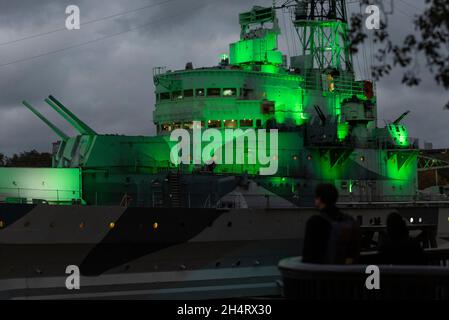 London, Großbritannien. 4. November 2021. Die HMS Belfast ist grün beleuchtet, um die Aufmerksamkeit auf die UN-Klimakonferenz (COP26) zu lenken, die in Glasgow stattfindet. Mehrere andere britische Kulturinstitutionen beteiligen sich ebenfalls an der Aktion, die Teil von Art for Your World ist, einer neuen Bewegung des WWF, die den Kunst- und Kultursektor im Kampf gegen den Klimawandel engagiert. Kredit: Stephen Chung / Alamy Live Nachrichten Stockfoto