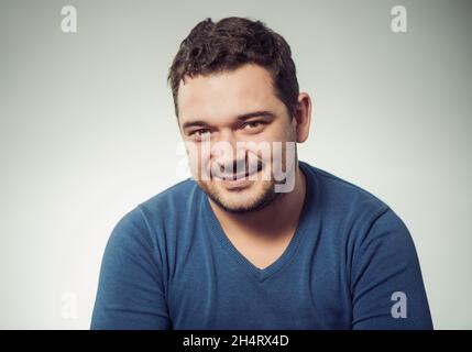 Junge positive Mann Porträt in blauen Pullover im Studio-Hintergrund Stockfoto