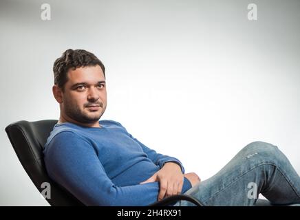 Junge positive Mann Porträt in blauen Pullover im Studio-Hintergrund Stockfoto