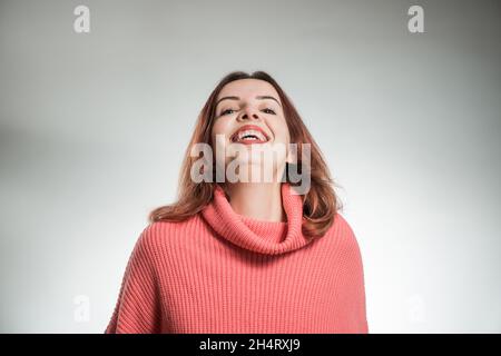 Junge lachende Frau Porträt in rosa Pullover auf Studio-Hintergrund Stockfoto
