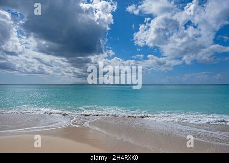 Seascape mit Sandstrand, azurblauem Wasser, weißen Wolken und der Insel Montserrat von Antigua, den Kleinen Antillen im Karibischen Meer aus gesehen Stockfoto