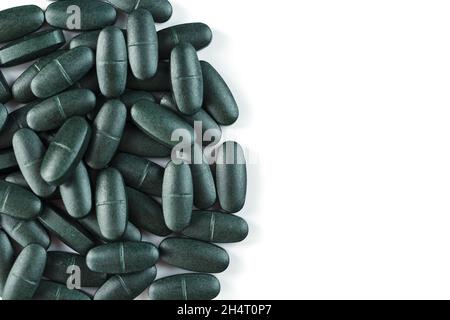 Grüne Tabletten mit Vitaminen und Spirulina für Männer auf weißem Hintergrund. Multivitamine für die Gesundheit von Männern, isolieren, freien Raum Stockfoto