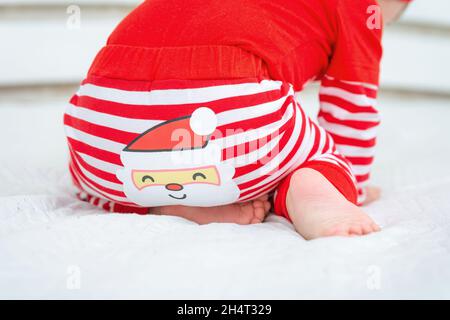 Rückansicht eines kleinen Kindes mit dem Weihnachtsmann auf der Hose auf weißem Hintergrund. Weihnachtsbaby in rot-weißem Anzug. Frohe Weihnachten und ein glückliches neues Y Stockfoto