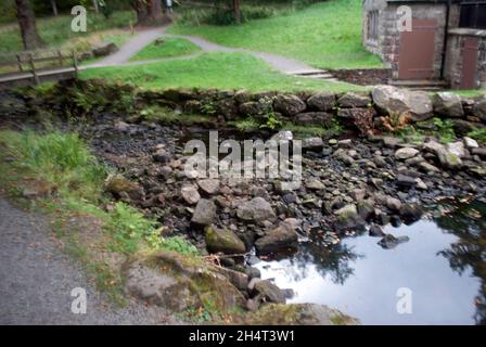 Rocks Lake und Gebäude in der Nähe von Schraubenturbine in Cragside, Rothbury, Northumberland, England, Großbritannien, Vereinigtes Königreich Stockfoto