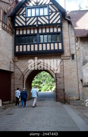 Drei Personen, die durch einen Tudor-Erweckungsbogen in Cragside, Rothbury, Northumberland, England, Großbritannien, Vereinigtes Königreich Stockfoto