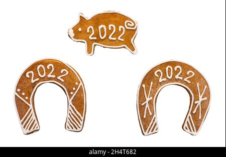 Verzierte Hufeisen und niedliches Schweinchen für 2022 glückliches Neujahr isoliert auf weißem Hintergrund. Set von gebackenen süßen Weihnachts Lebkuchen für Viel Glück. Stockfoto
