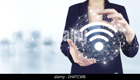 WLAN-Konzept. Virtuelles holographisches Wi-Fi-Symbol mit zwei Händen und hellem unscharfem Hintergrund. Kostenloses WLAN-Netzwerk Signaltechnologie Internet Co Stockfoto