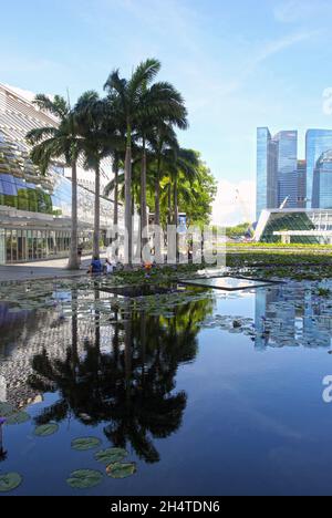 Ein Blick auf das Einkaufszentrum Shoppes in Marina Bay Sands auf der linken Seite und Singapurs Finanzviertel im Hintergrund. Stockfoto