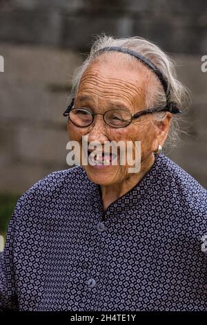 Eine ältere chinesische Frau in traditioneller Kleidung in der Nähe der Stadt Xingping, China. Stockfoto