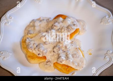 Auf einem weißen Teller mit einer gewürfelten Milchgravie mit Schweinewurst über Keksen. Stockfoto